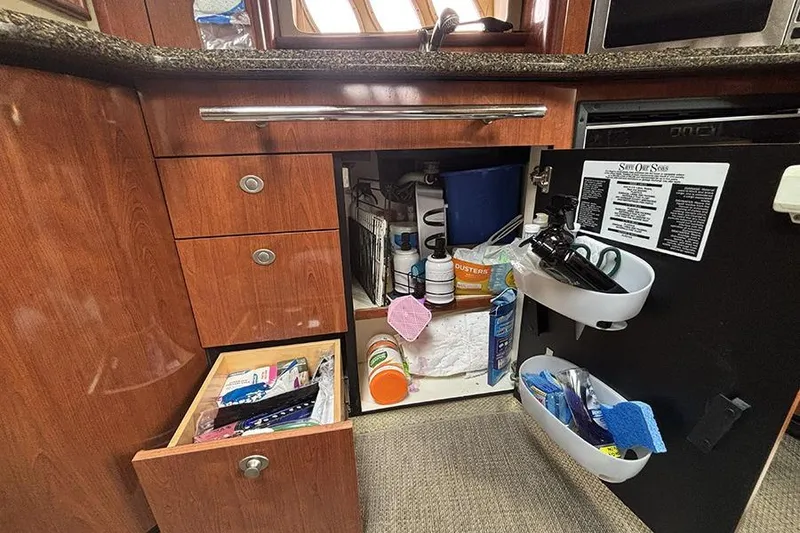 Slide: The Image of Cabinet storage in 2006 Sea Ray 44 Sundancer yacht kitchen, with cleaning supplies and utensils. - 32