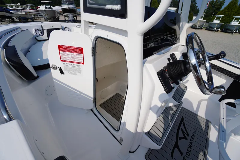 Slide: The Image of 2026 Tidewater 210 CC Adventure boat interior with open storage compartment and steering wheel. - 21