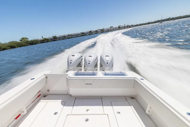 Slide: The Image of 2021 Contender 39FA Fish Around boat speeding on water with triple outboard engines. - 24