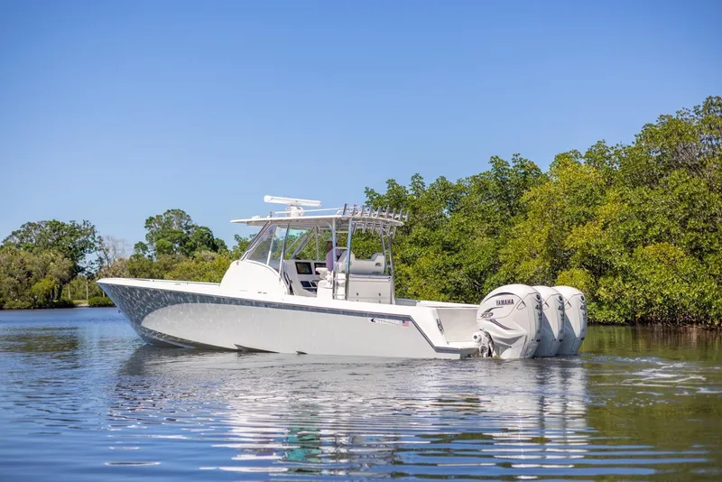 Slide: The Image of 2021 Contender 39FA Fish Around boat on calm water near lush greenery. - 7