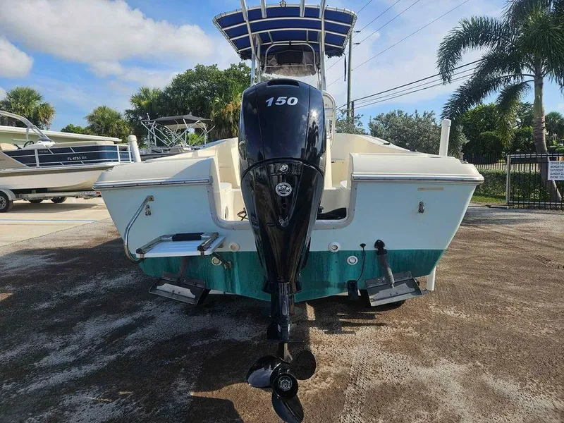 Slide: The Image of 2014 Key Largo 2100 boat with 150 HP outboard motor, parked outdoors. - 2
