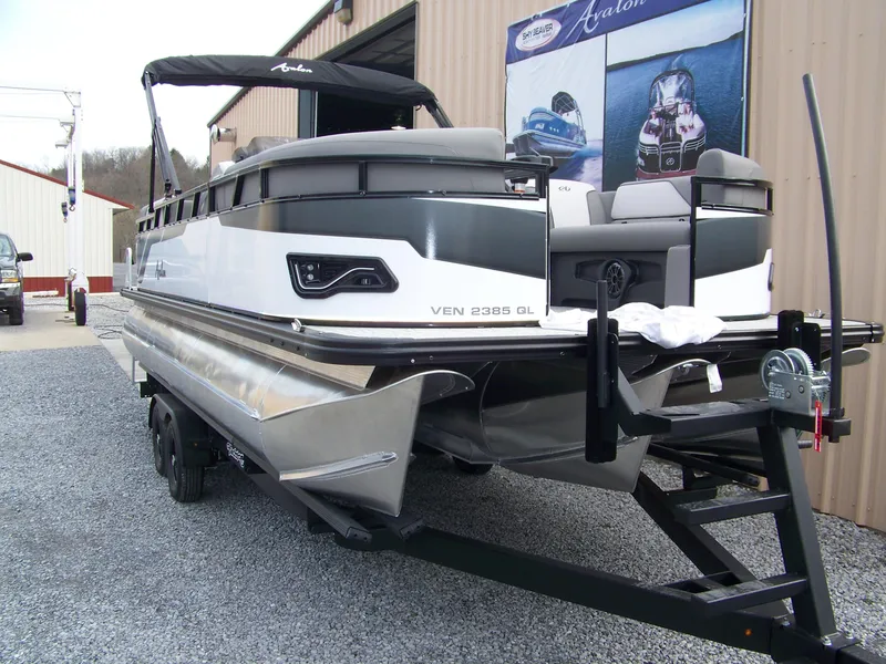 Slide: The Image of 2024 Avalon VENTURE 85 QL pontoon boat on a trailer outside a warehouse. - 4