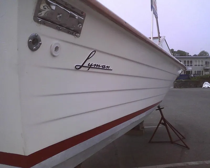 Slide: The Image of 1978 Lyman 24 Sportsman boat with white hull and red trim, docked on land. - 12