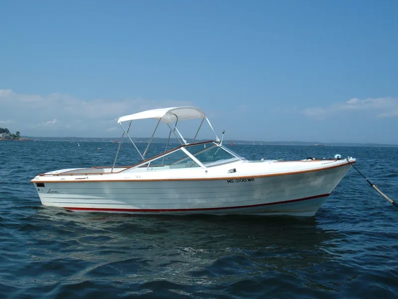 Slide: The Image of 1978 Lyman 24 Sportsman boat on calm water under clear blue sky. - 13