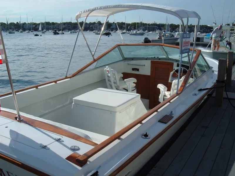 Slide: The Image of 1978 Lyman 24 Sportsman boat docked at a marina with canopy and seating. - 2