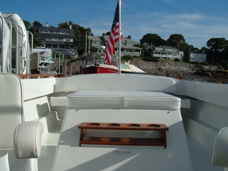 Slide: The Image of 1978 Lyman 24 Sportsman boat with American flag, docked near coastal homes. - 7