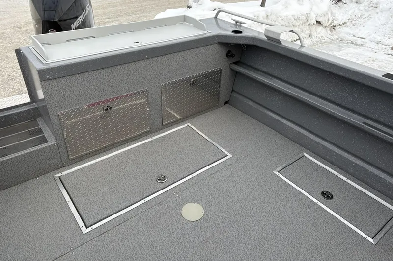 Slide: The Image of 2024 Spartan 240 Maximus Pro boat interior with storage compartments and snow background. - 7