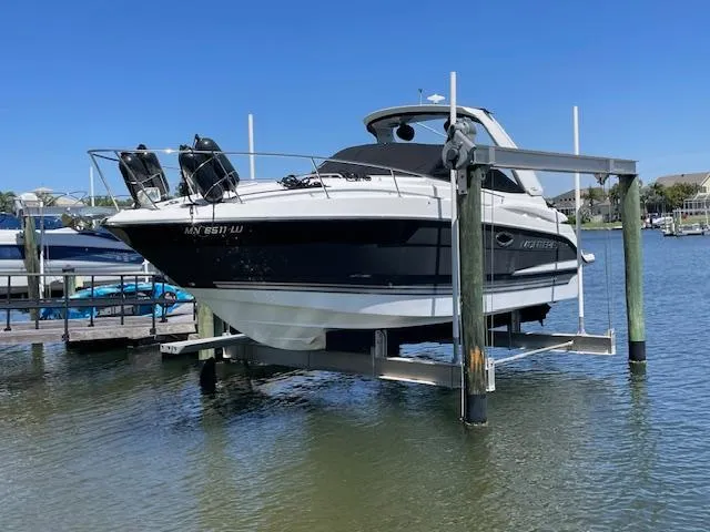 The Image of 2019 Monterey 295 boat on lift, docked in marina under clear blue sky. - 0