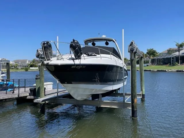 Slide: The Image of 2019 Monterey 295 boat on lift, docked by waterfront homes under clear blue sky. - 1