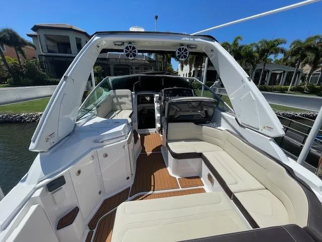 Slide: The Image of 2019 Monterey 295 boat interior with spacious seating and modern design, docked near waterfront homes. - 11