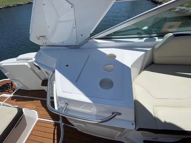 Slide: The Image of 2019 Monterey 295 boat interior with seating and cup holders, docked by the water. - 14
