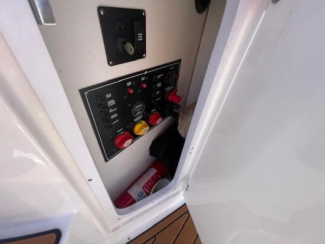 Slide: The Image of Control panel inside a 2019 Monterey 295 boat, featuring switches and a fire extinguisher. - 17
