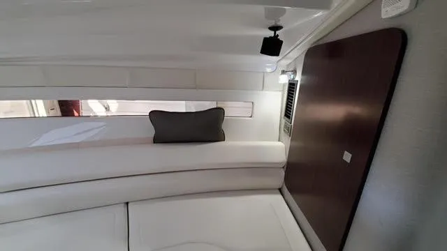 Slide: The Image of 2019 Monterey 295 interior cabin with white seating and dark wood accents. - 30