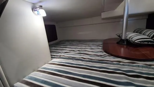 Slide: The Image of 2019 Monterey 295 cabin interior with striped bedding and ambient lighting. - 37