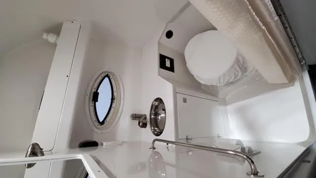 Slide: The Image of 2019 Monterey 295 boat interior with porthole, sink, and compact bathroom amenities. - 41