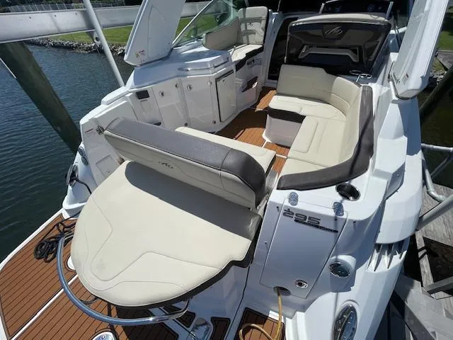 Slide: The Image of 2019 Monterey 295 boat interior with white seating and wood deck, docked by the water. - 7