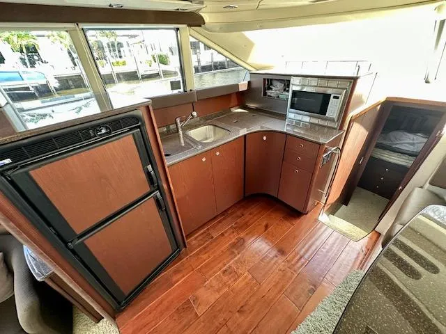 Slide: The Image of 2013 Meridian 441 Sedan yacht kitchen with wood flooring, sink, microwave, and refrigerator. - 13