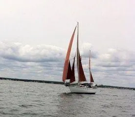 Slide: The Image of 1976 Westsail Ketch sailing on a cloudy day with red sails. - 11