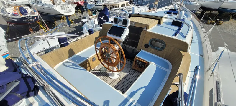Slide: The Image of 1976 Westsail Ketch sailboat cockpit with wooden wheel and modern navigation equipment. - 22