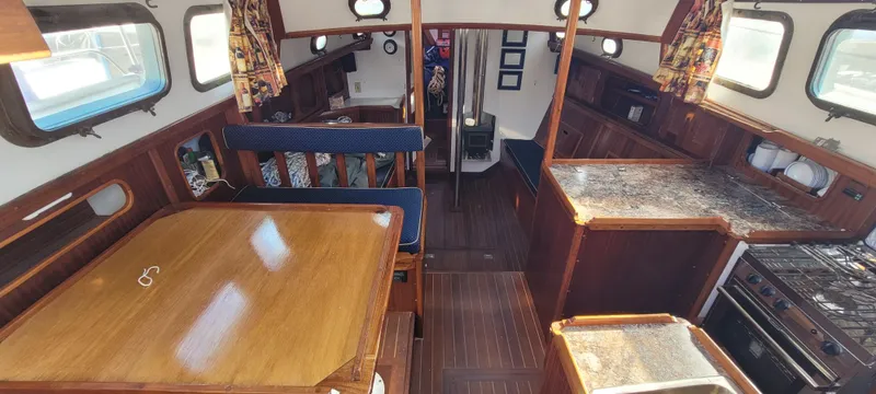 Slide: The Image of Interior of a 1976 Westsail Ketch, featuring a cozy dining and kitchen area. - 42