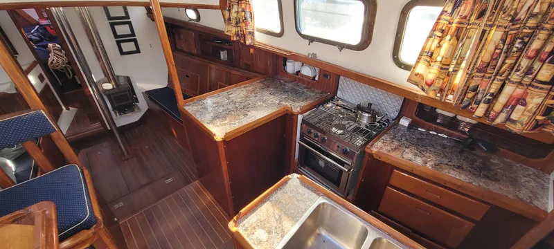 Slide: The Image of Interior of a 1976 Westsail Ketch, featuring a well-equipped kitchen with wood accents. - 43