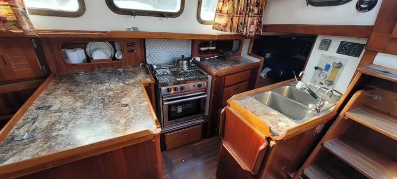 Slide: The Image of 1976 Westsail Ketch interior kitchen with stove, sink, and wooden cabinetry. - 45