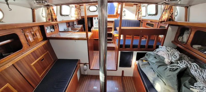 Slide: The Image of 1976 Westsail Ketch interior with wooden finishes, seating, and nautical equipment. - 47