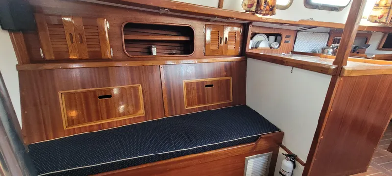 Slide: The Image of 1976 Westsail Ketch interior with wooden cabinetry and cushioned seating. - 48