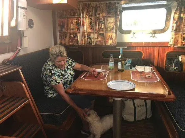 Slide: The Image of Woman in a 1976 Westsail Ketch cabin, petting a dog at the dining table. - 5