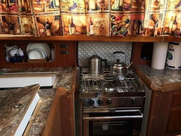 Slide: The Image of 1976 Westsail Ketch galley with stove, cookware, and decorative curtains. - 6