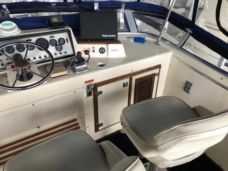 Slide: The Image of 1986 Chris-Craft Catalina boat cockpit with steering wheel, control panel, and seating. - 13