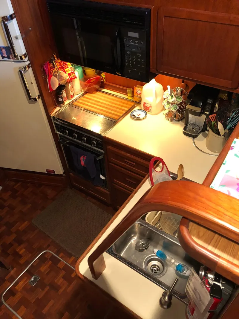 Slide: The Image of 1986 Chris-Craft Catalina boat kitchen with stove, sink, and wooden cabinetry. - 22