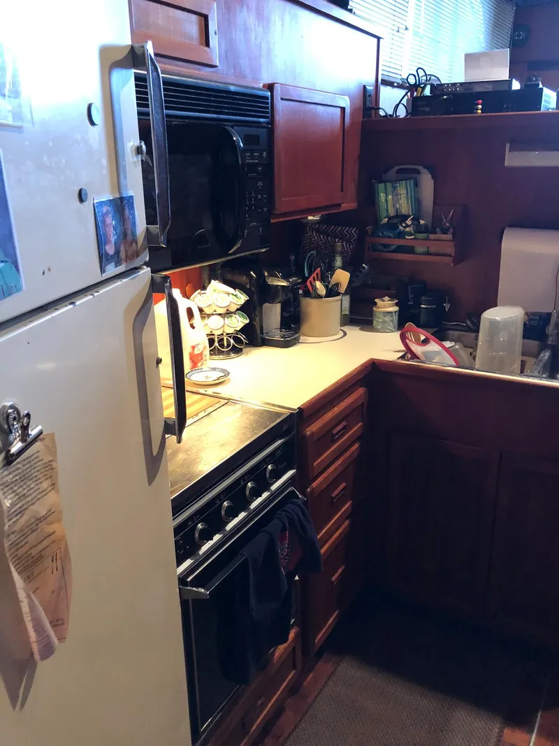 Slide: The Image of 1986 Chris-Craft Catalina boat kitchen with wooden cabinets and appliances. - 24