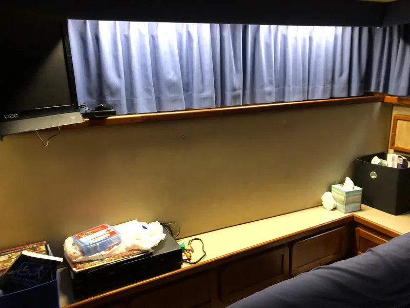 Slide: The Image of Interior of 1986 Chris-Craft Catalina boat with blue curtains and storage area. - 37