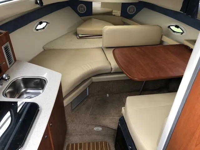 Slide: The Image of 2007 Bayliner 275 interior cabin with kitchenette, dining table, and seating area. - 18