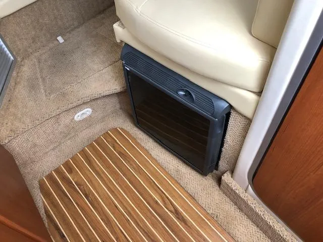Slide: The Image of Interior of a 2007 Bayliner 275 boat showing a small refrigerator and carpeted flooring. - 21