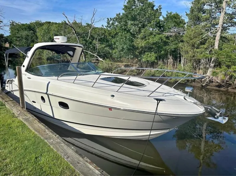 The Image of 2013 Sea Ray Sundancer boat docked by a lush, wooded shoreline. - 0