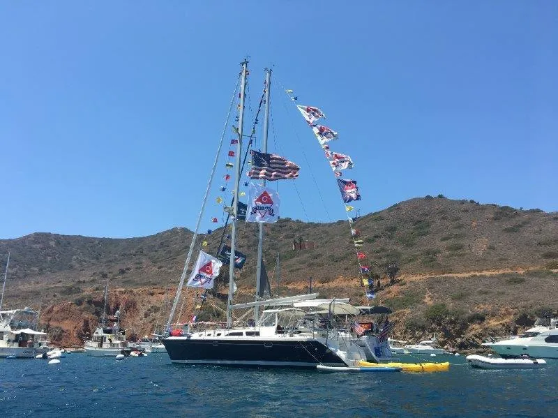 Slide: The Image of 2007 Catalina MkII sailboat with flags anchored near rocky coastline. - 48
