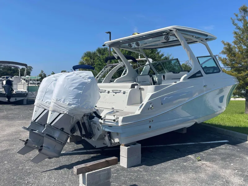 Slide: The Image of 2024 Crownline 260 DC boat on blocks, dual engines covered, parked outdoors. - 3