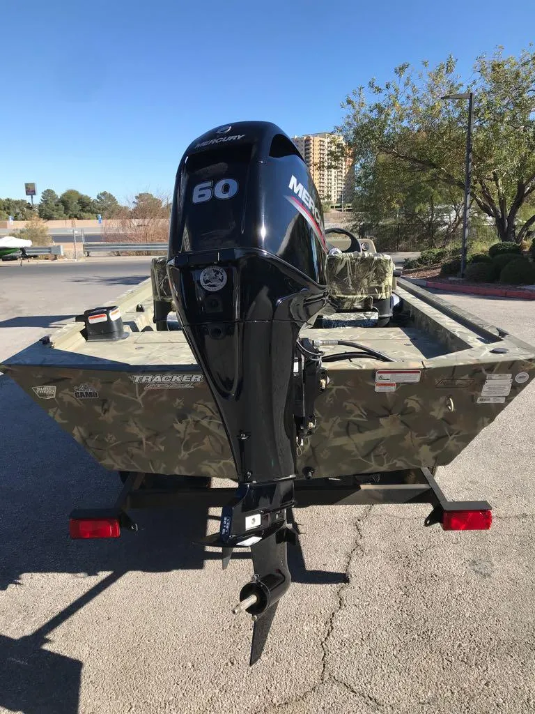 Slide: The Image of 2024 Tracker Grizzly 1754 SC boat with Mercury 60 outboard motor, parked outdoors. - 3