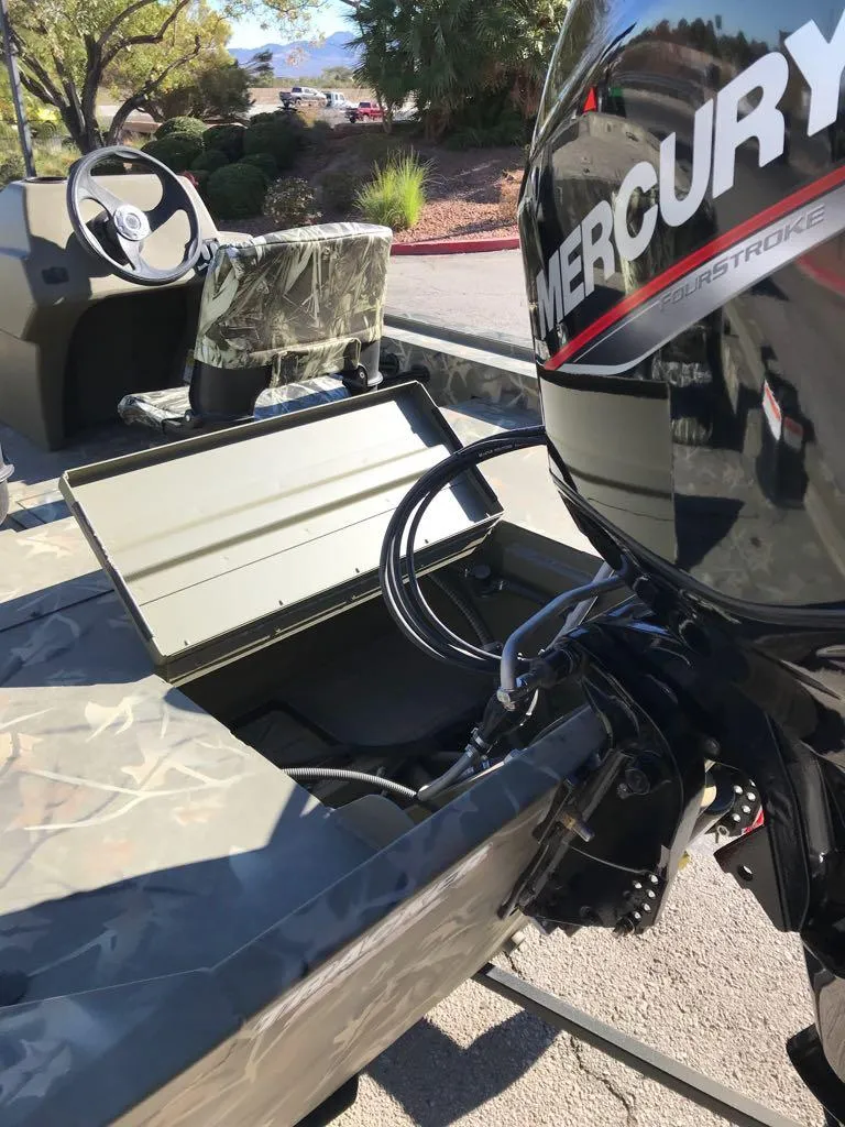 Slide: The Image of 2024 Tracker Grizzly 1754 SC boat with Mercury engine, camo seats, and storage compartment. - 7