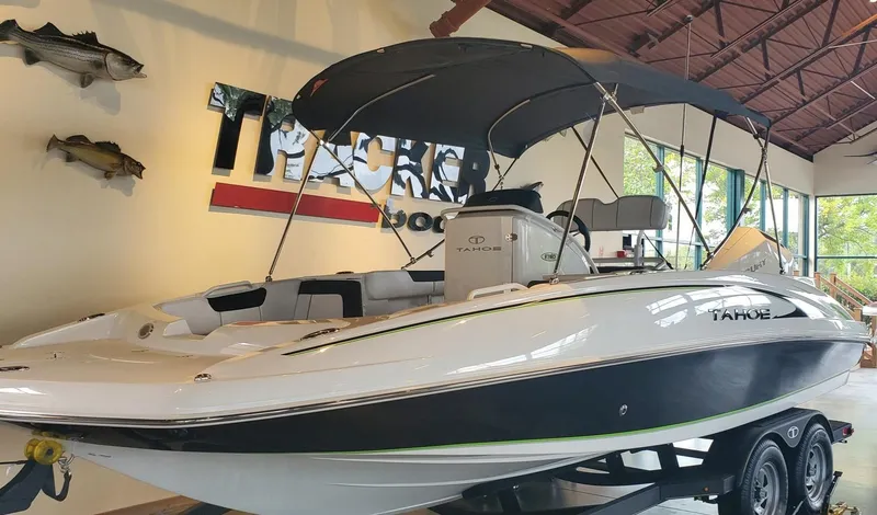 Slide: The Image of 2024 Tahoe 2150 CC boat displayed indoors with canopy and trailer. - 1
