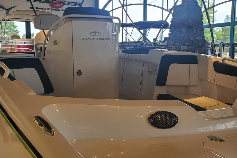 Slide: The Image of 2024 Tahoe 2150 CC boat interior with seating and helm in showroom. - 9