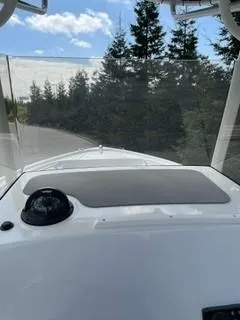 Slide: The Image of 2023 Mako 214 CC boat dashboard with compass, windshield, and forested background. - 11