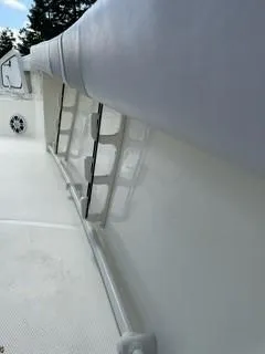 Slide: The Image of 2023 Mako 214 CC boat interior with rod holders and cushioned side rail. - 12