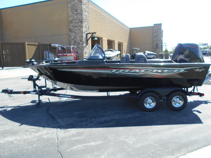 Slide: The Image of 2024 Tracker Targa V-19 WT fishing boat on trailer, parked outside a building. - 2