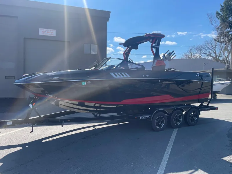 Slide: The Image of 2021 Supra SE boat on a trailer in a parking lot. - 13