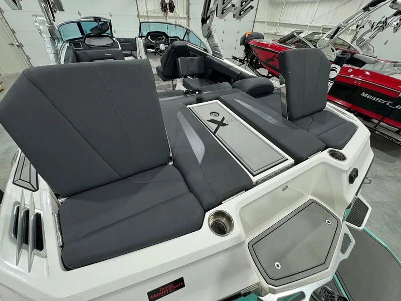 Slide: The Image of 2019 MasterCraft XStar boat interior with black seating and storage compartments. - 24