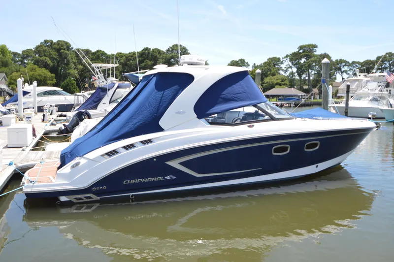 The Image of 2013 Chaparral 327 SSX boat docked in a marina, featuring a sleek blue and white design. - 0