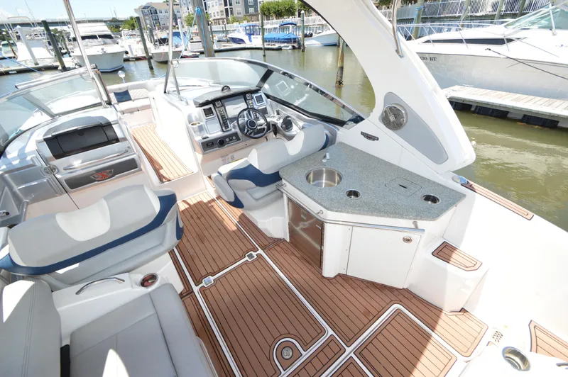 Slide: The Image of 2013 Chaparral 327 SSX boat interior with helm, seating, and kitchenette at marina. - 10